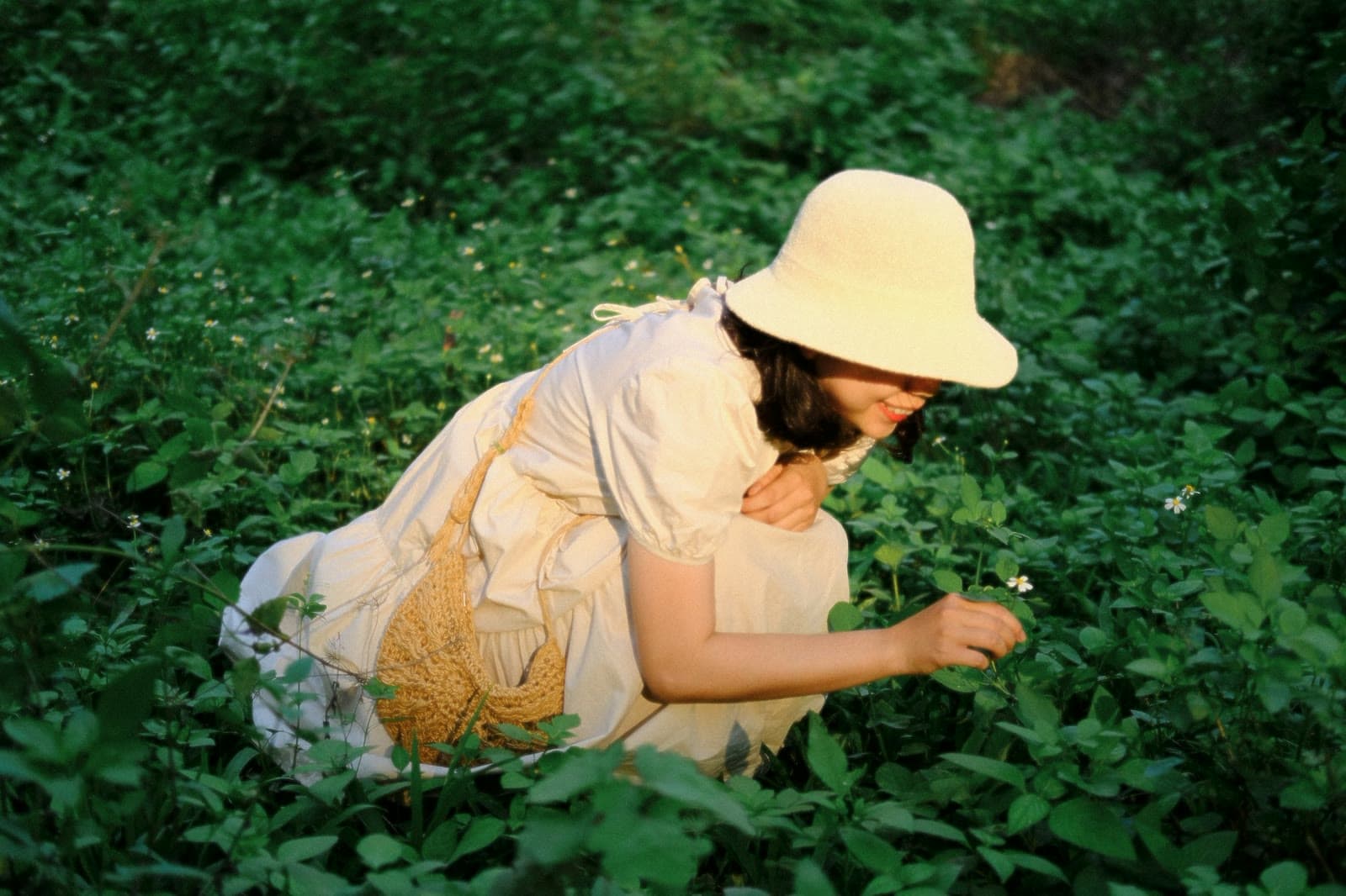 A woman gathering wild plants in a green field